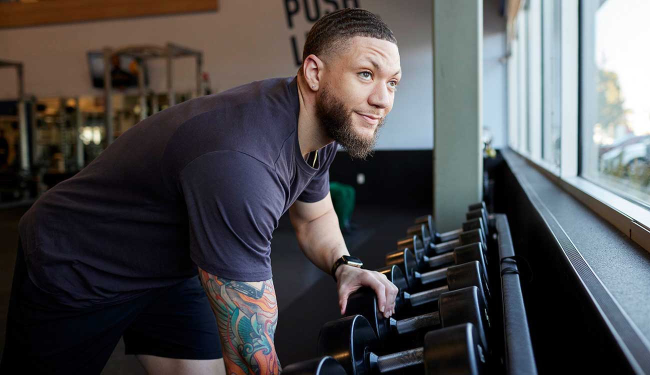 man grabbing dumbbell from rack